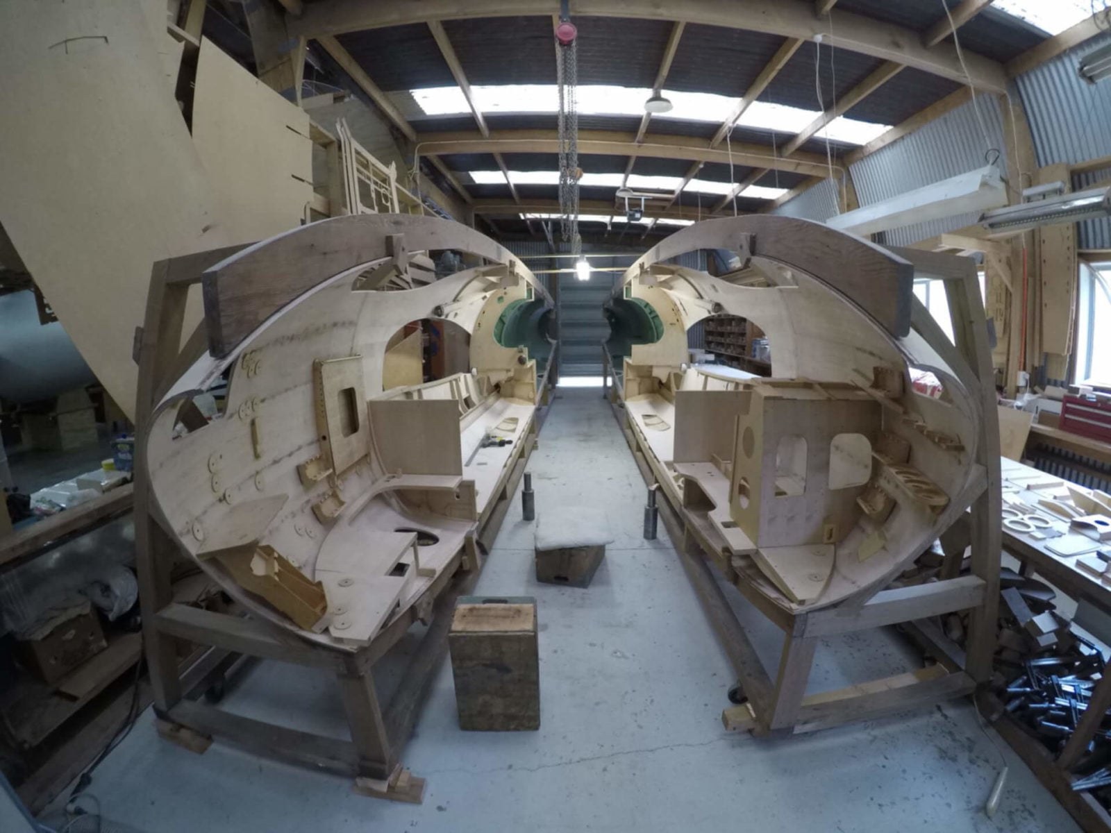 Wooden de Havilland Mosquito fuselage sections under construction in a workshop.