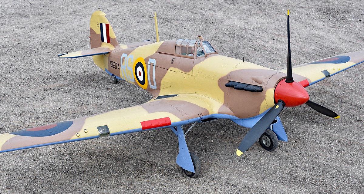 Tan and brown Hawker Hurricane on gravel with red spinner and RAF roundels.