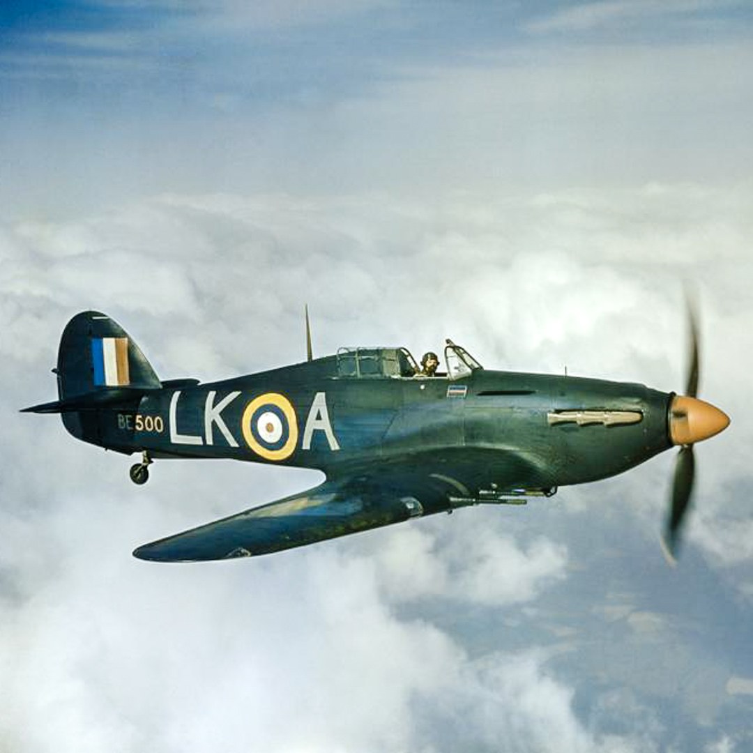 Dark camouflaged Hawker Hurricane BE500 marked LK-A flying near clouds.