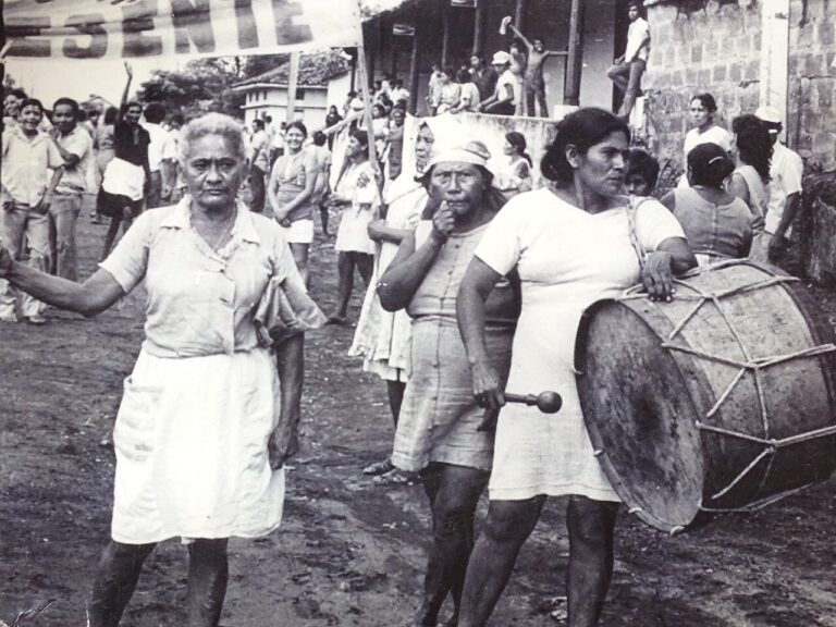 Women marching with a drum in León