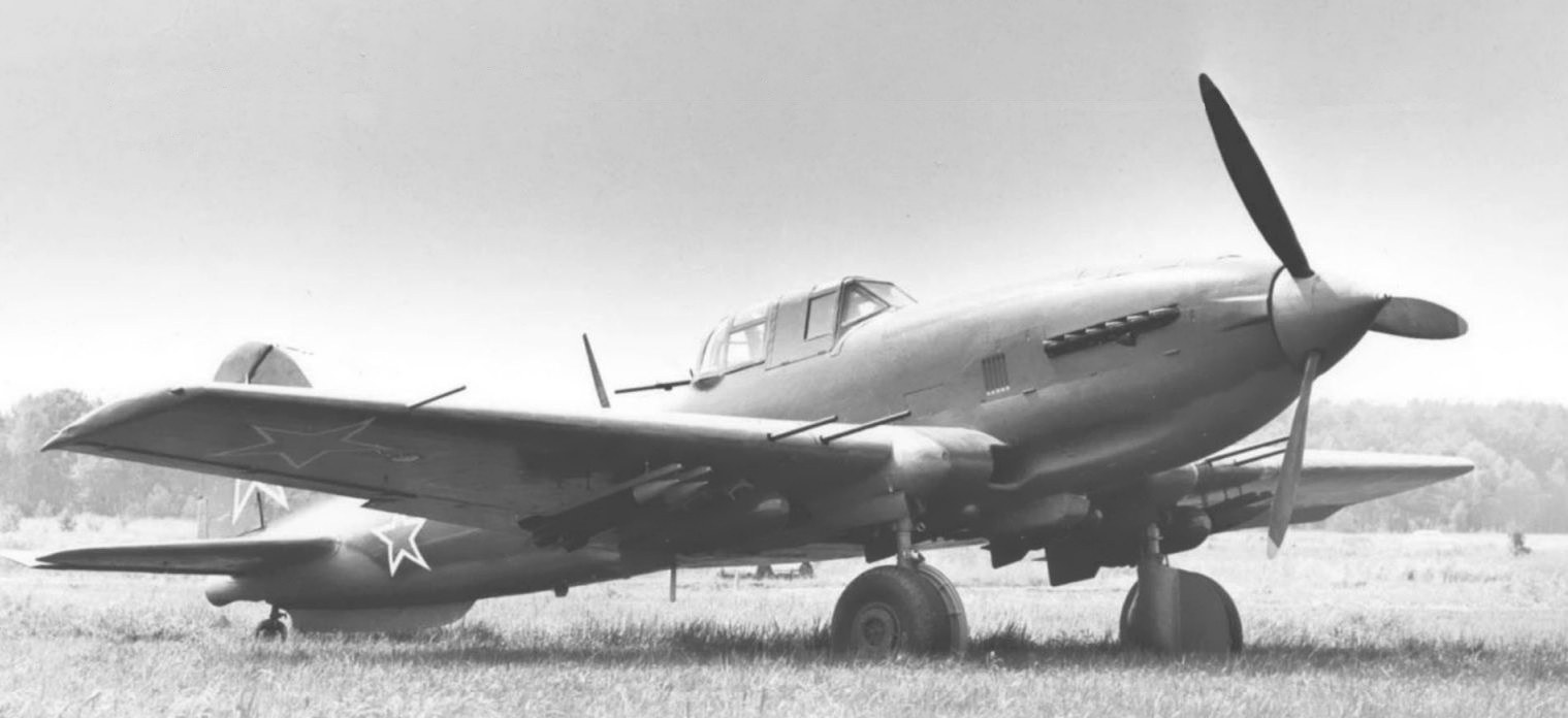 Black-and-white image of Soviet-marked Ilyushin Il-10 parked on grass.