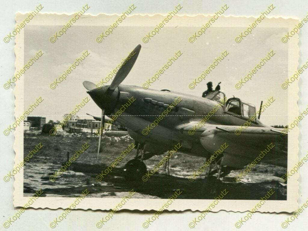 Black-and-white photo of an Ilyushin Il-2 on rough ground with rear gunner visible.