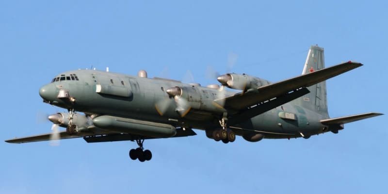 Grey-green Ilyushin Il-20 flying with landing gear extended and red star tail marking.