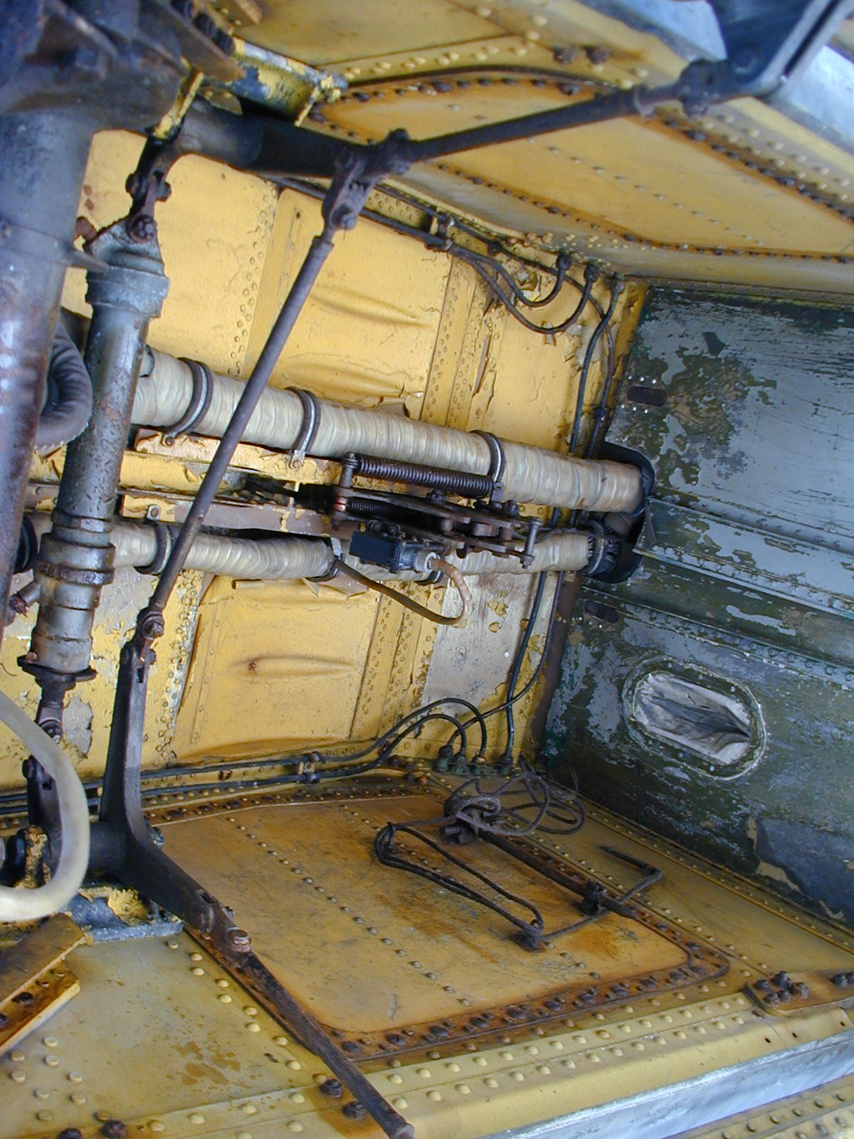 Close view inside an Ilyushin Il-28 interior bay with yellow riveted panels and tubing.