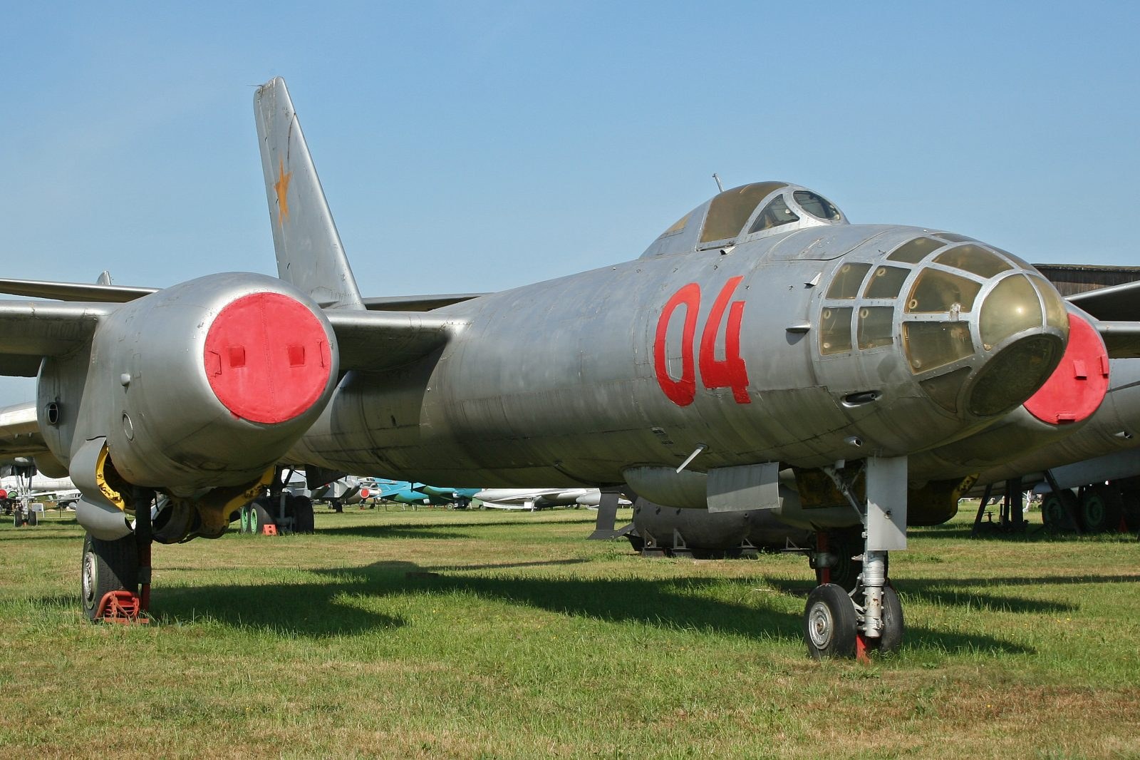 Close front-quarter view of grey Ilyushin Il-28 number 04 with red intake covers.