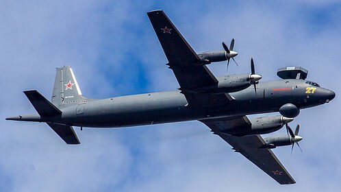 Dark grey Ilyushin Il-38 marked yellow 27 flying with red star markings.