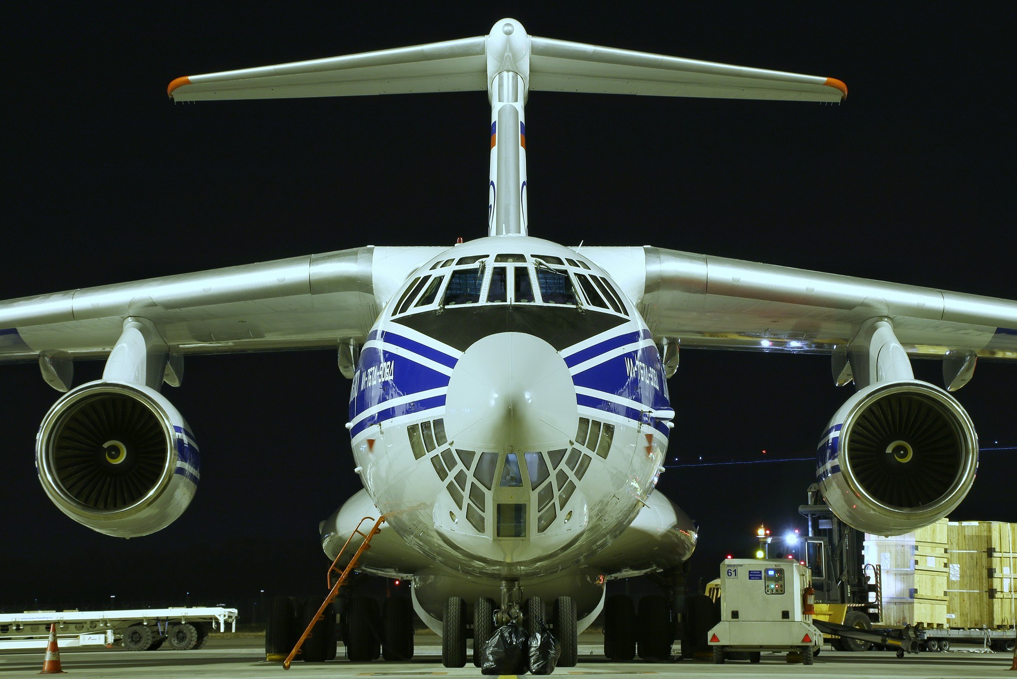 Night front view of a Volga-Dnepr Ilyushin Il-76 parked with cargo equipment nearby.