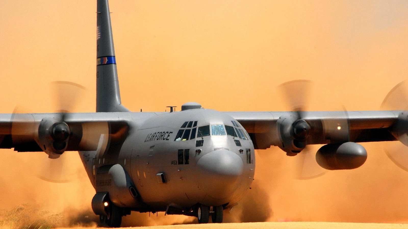 U.S. Air Force Lockheed C-130 Hercules moving through dust on a desert runway.