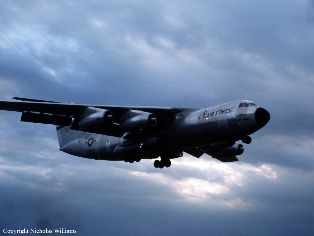 U.S. Air Force Lockheed C-141 Starlifter flying below dark clouds.