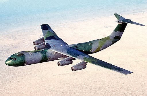 Camouflaged Lockheed C-141 Starlifter flying over desert terrain.