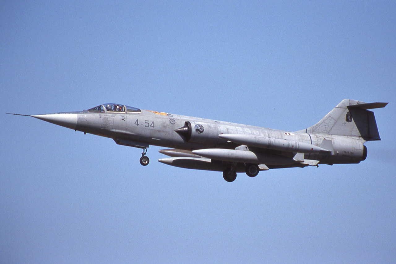 Grey F-104 Starfighter 4-54 flying with landing gear down.