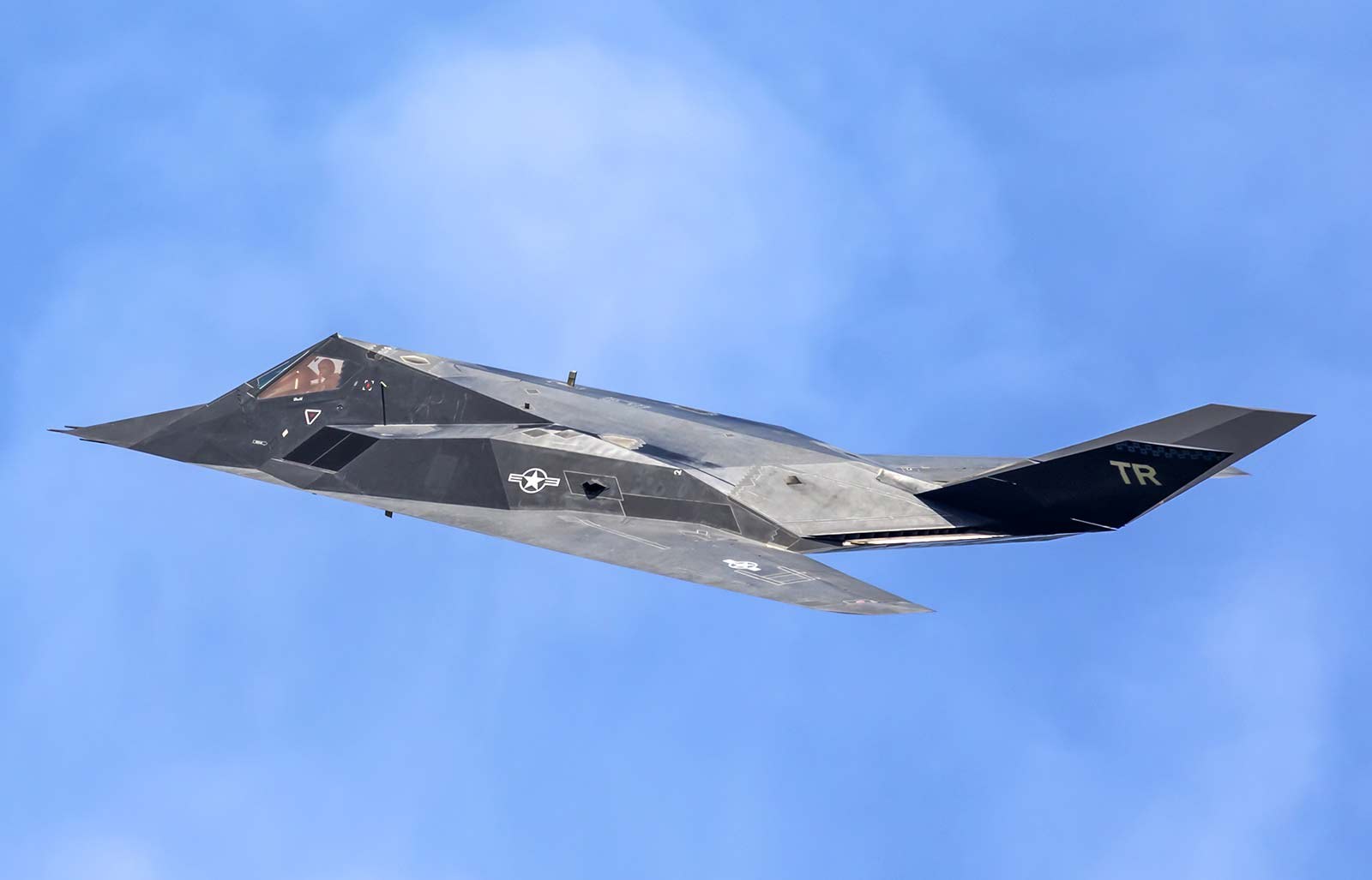 F-117 Nighthawk 843 flying against a blue sky.