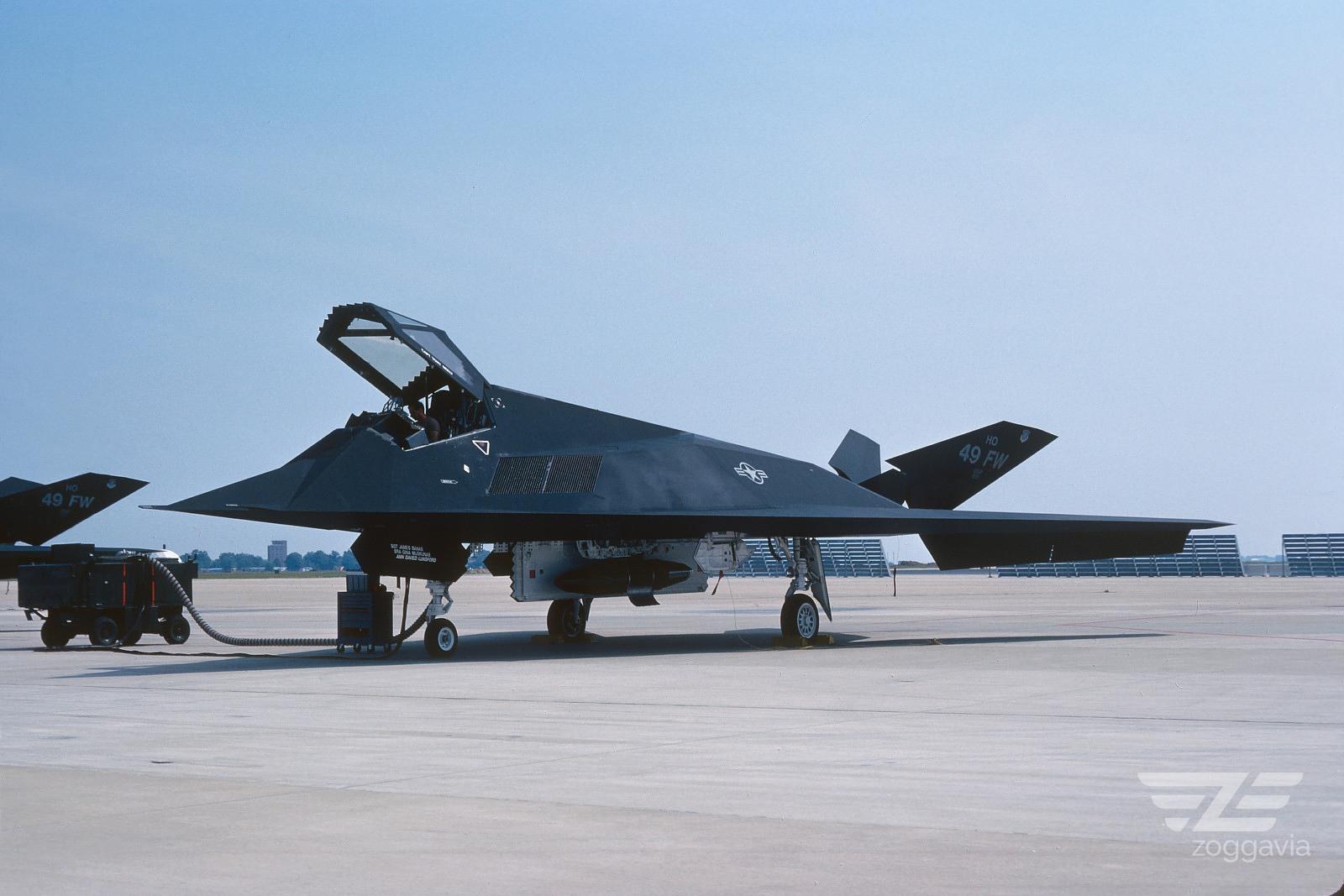 F-117 Nighthawk parked on a ramp with canopy open and ground equipment nearby.
