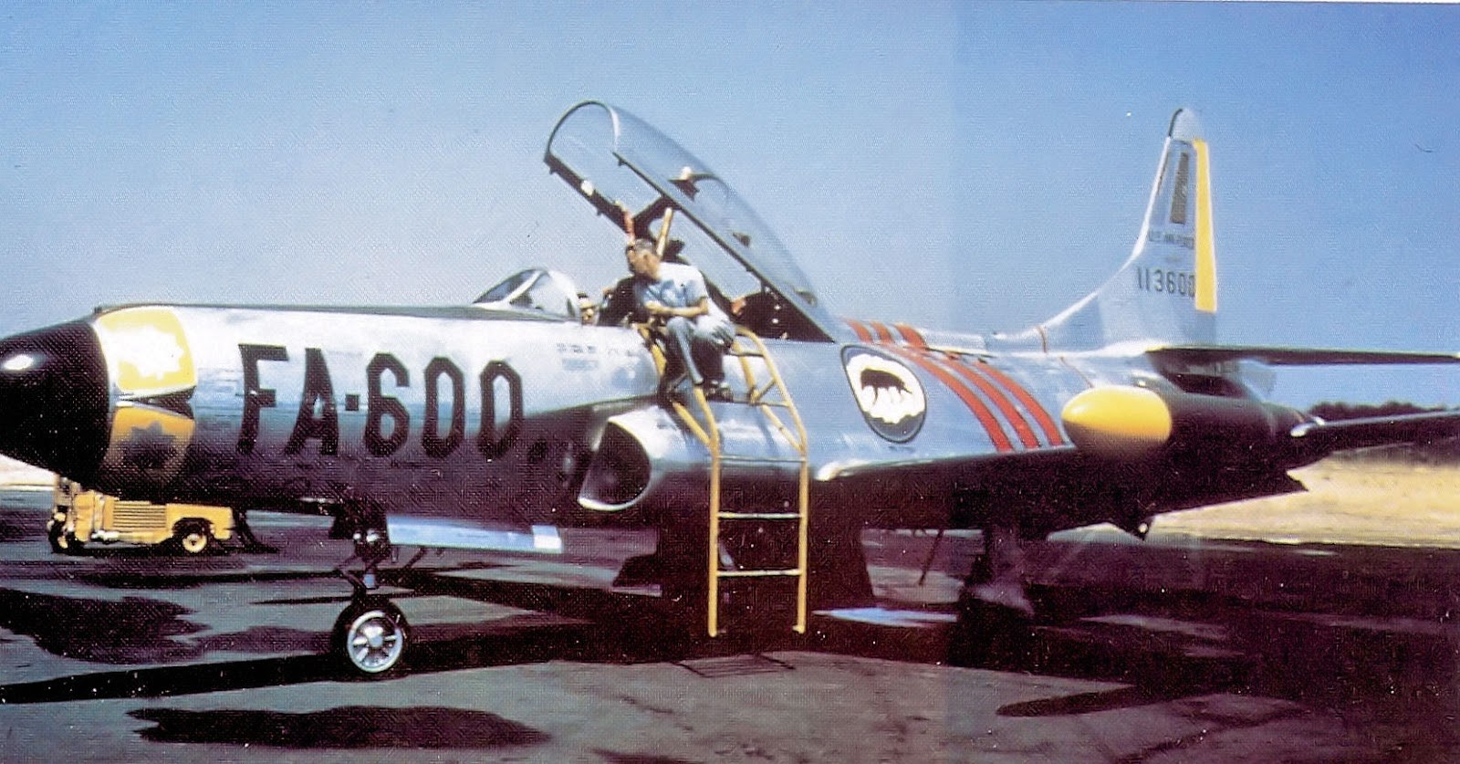 F-94 Starfire FA-600 parked with canopy open and a crewman on a ladder.