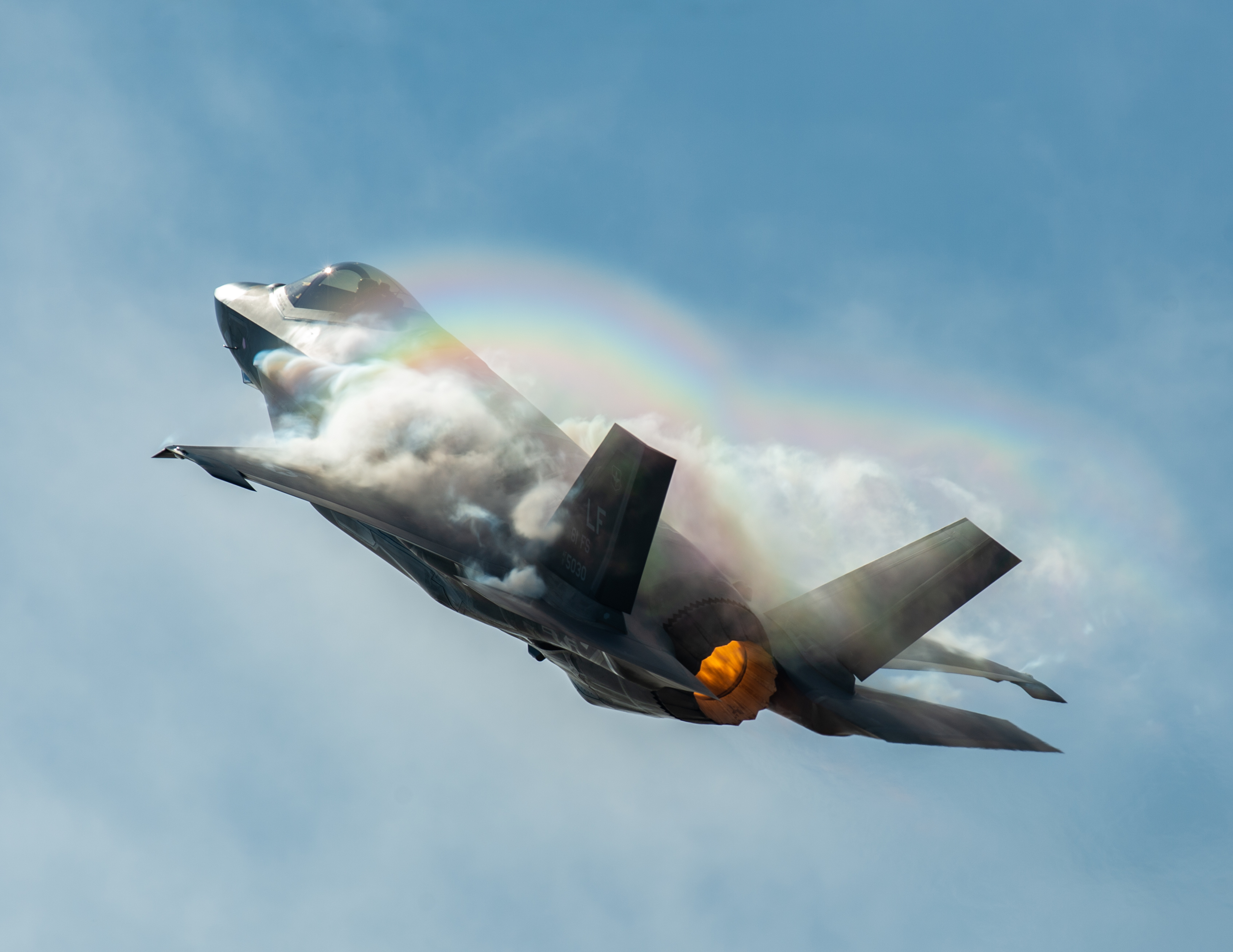 Lockheed Martin F-35 Lightning II climbing through vapor in a heritage-flight photograph, showing the aircraft in high-speed flight.