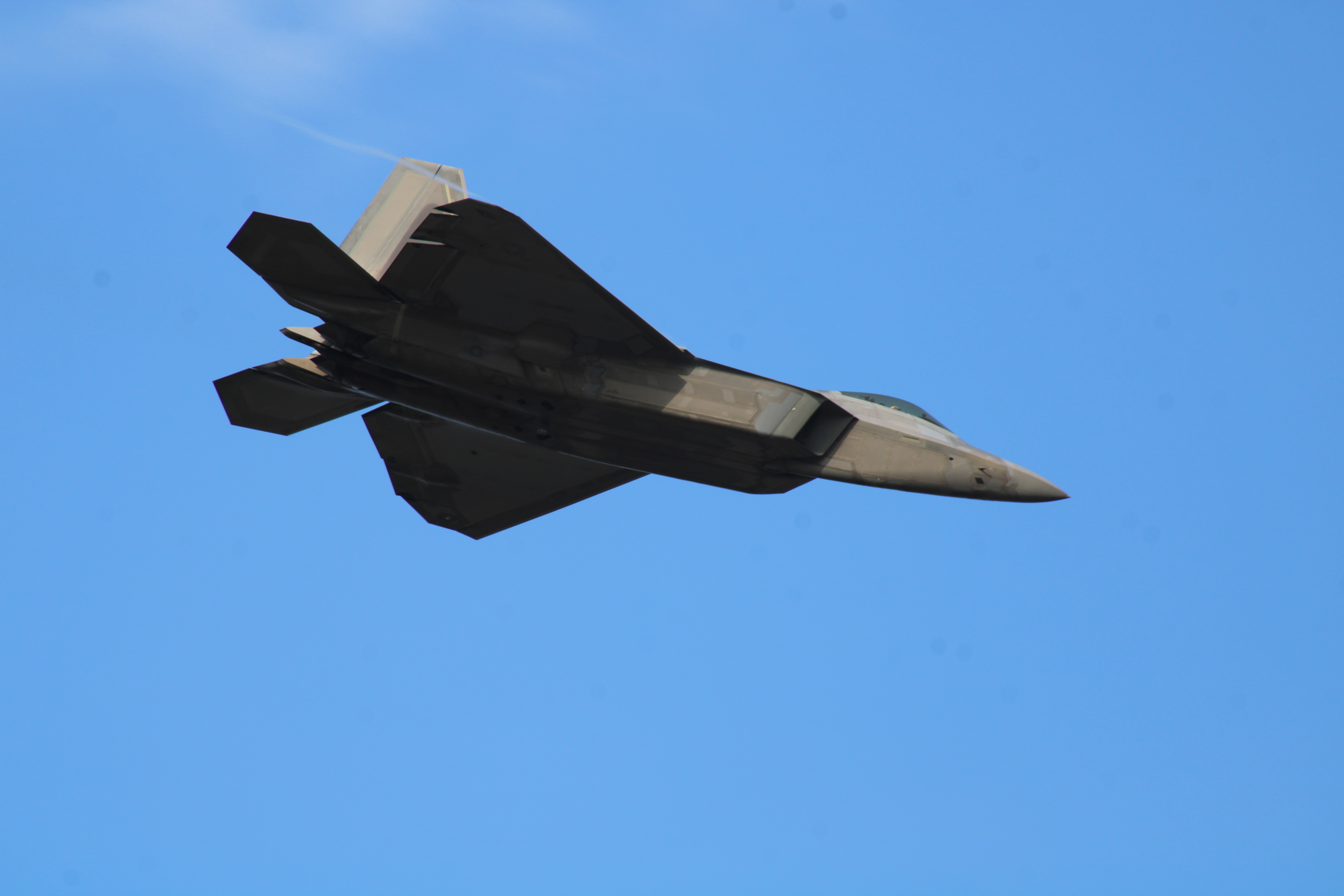 Lockheed Martin F-22 Raptor in flight against a clear sky, showing the stealth fighter's angular planform and twin-tail profile.