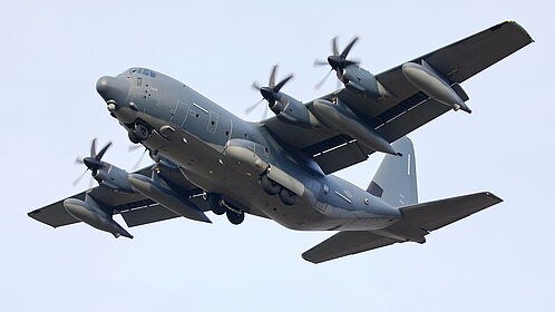 Grey C-130J Super Hercules banking with landing gear down.