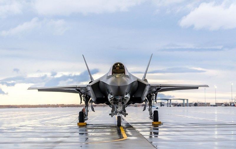 F-35 Lightning II parked head-on on a wet ramp with landing gear down.