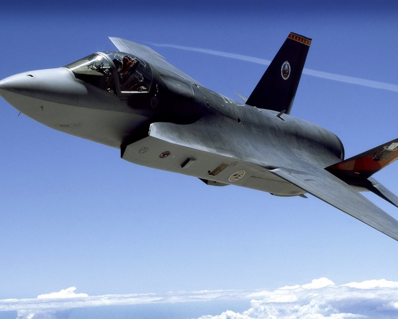 F-35 Lightning II passing close overhead with canopy and underside panels visible.