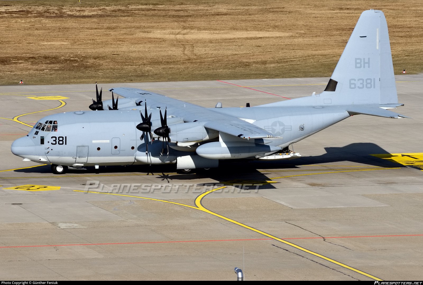 Marine KC-130J 381 taxiing on a concrete ramp.
