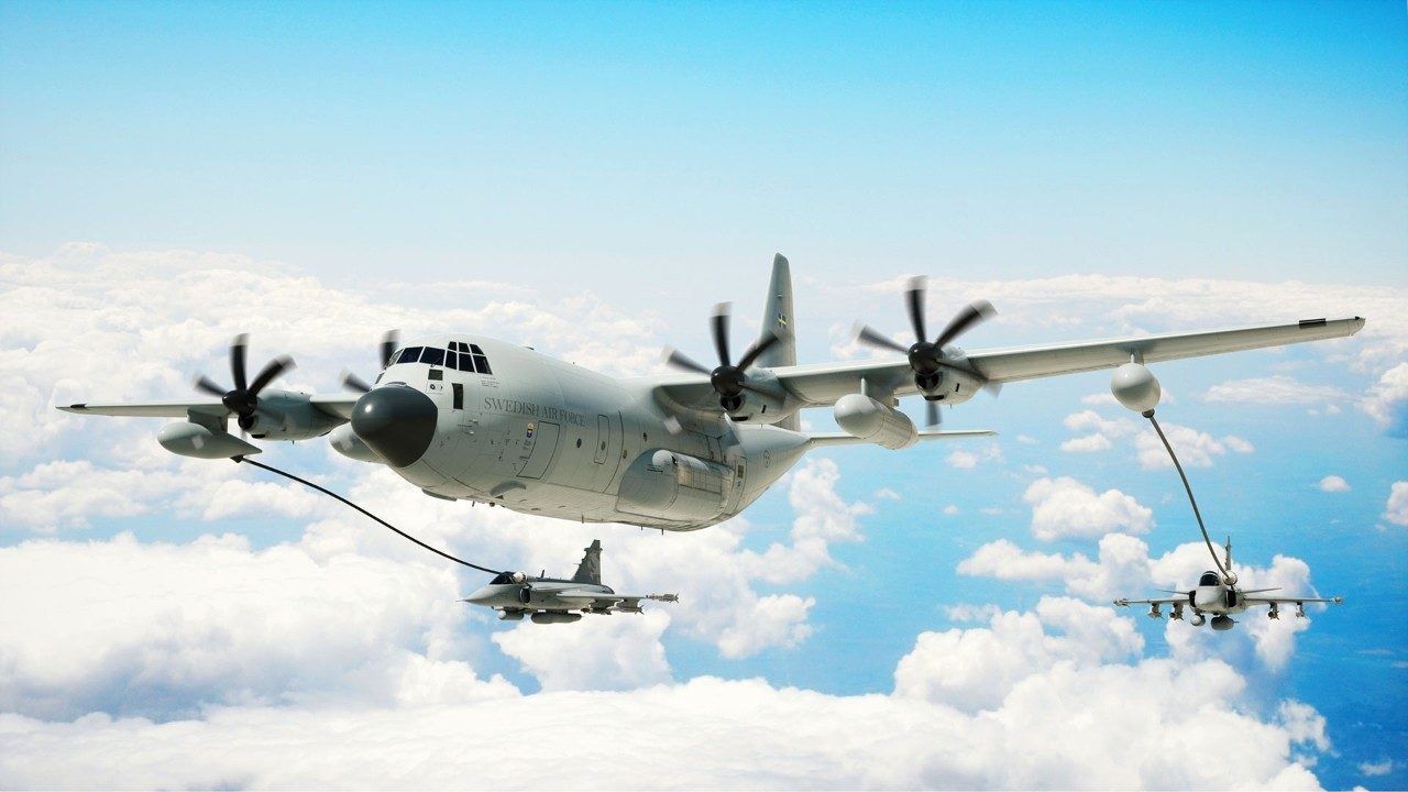 KC-130J flying above clouds with two jets connected to refueling hoses.