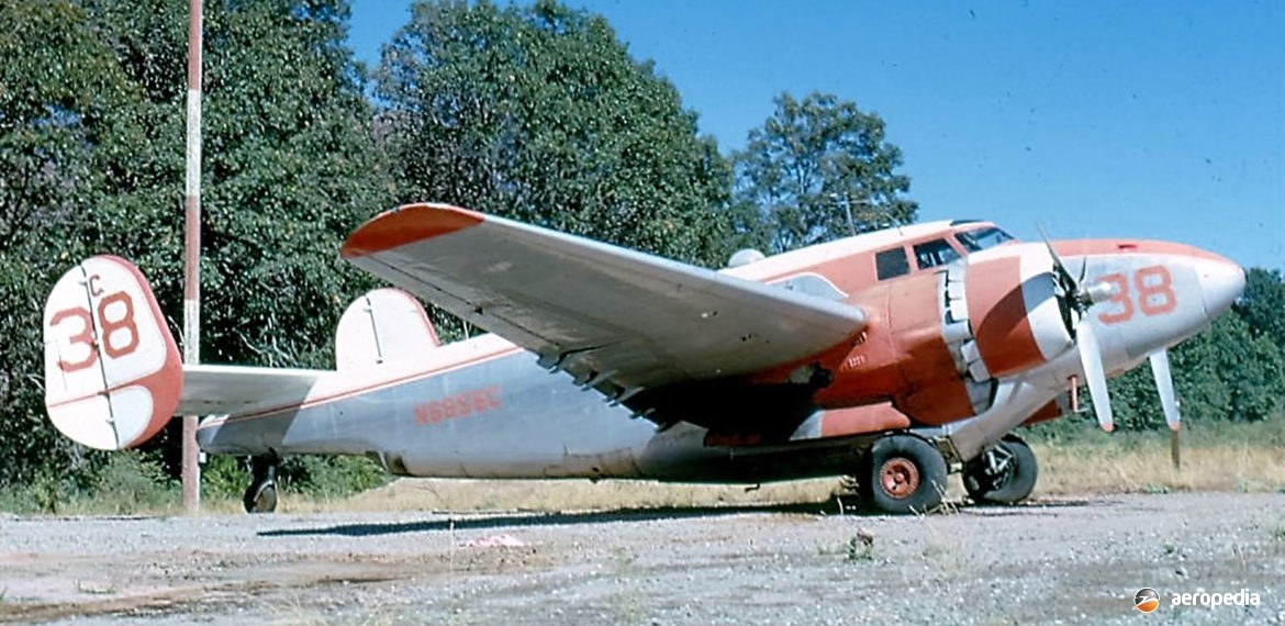 Red-and-white PV-2 Harpoon 38 parked on gravel near trees.