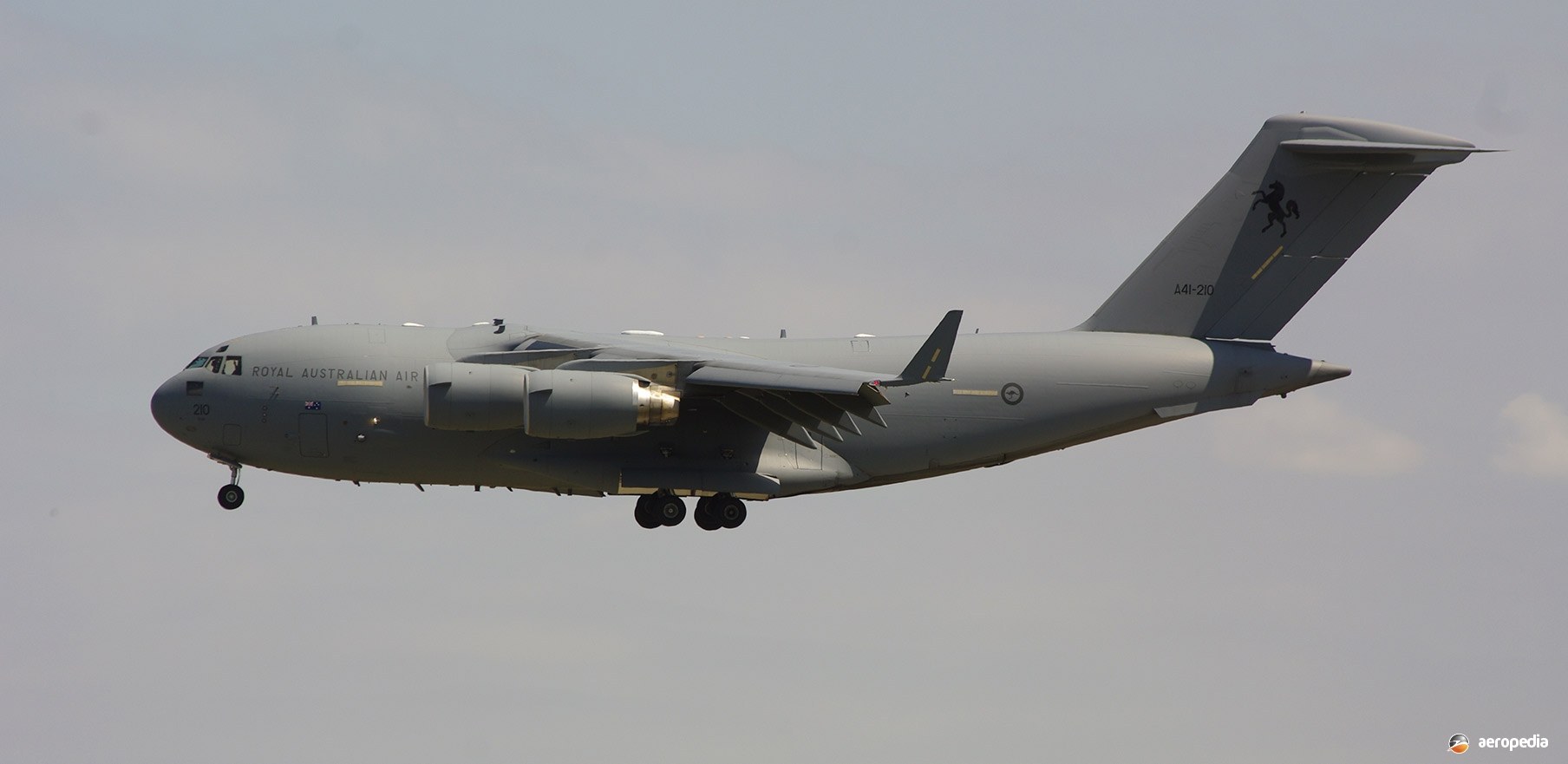 Grey C-17 Globemaster III approaching with landing gear down.