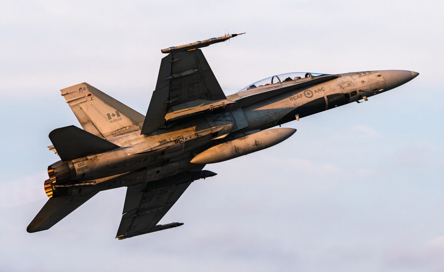 Canadian CF-18 Hornet banking steeply with underside and exhaust visible.