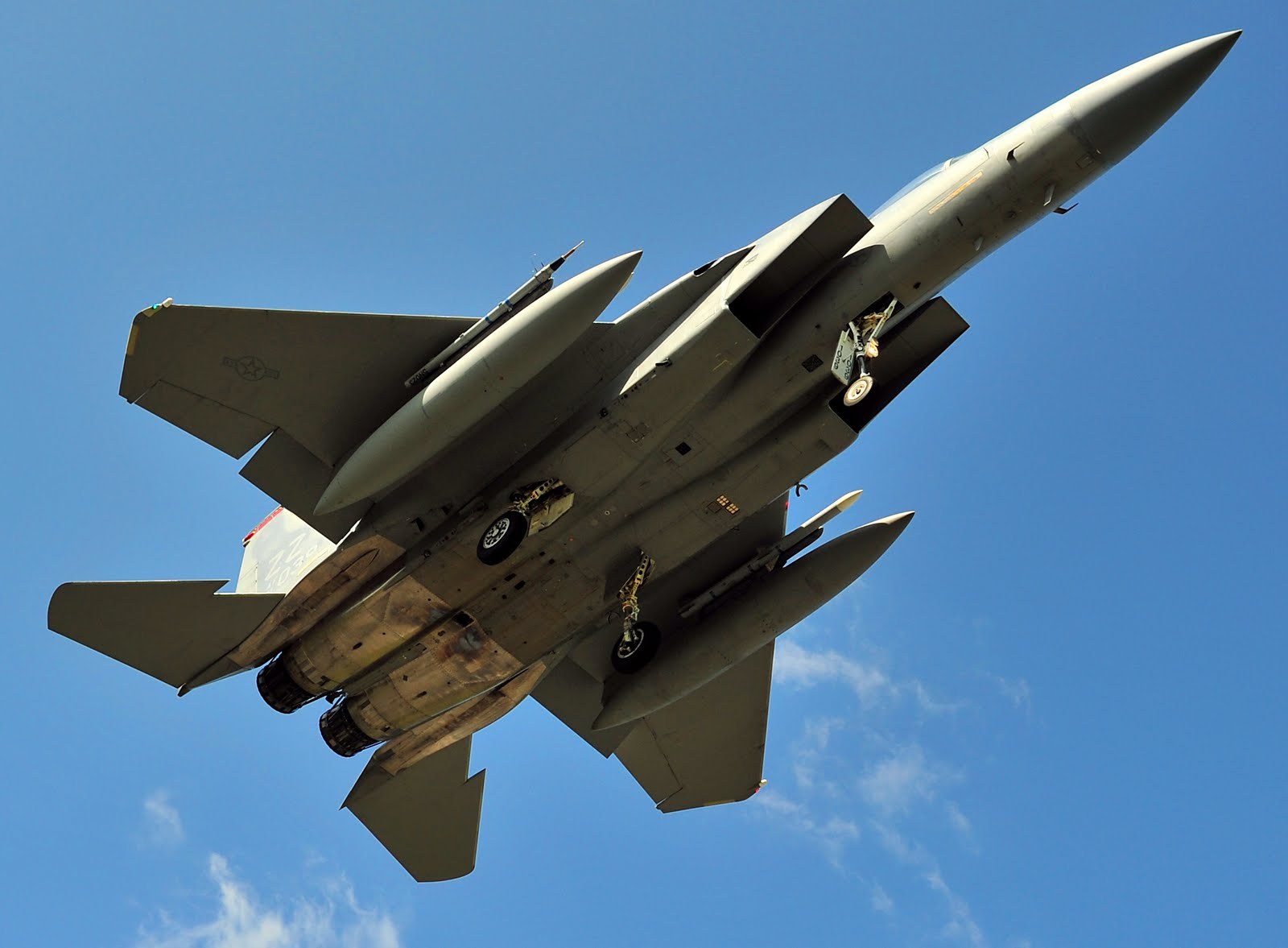 F-15 Eagle passing overhead with landing gear down.