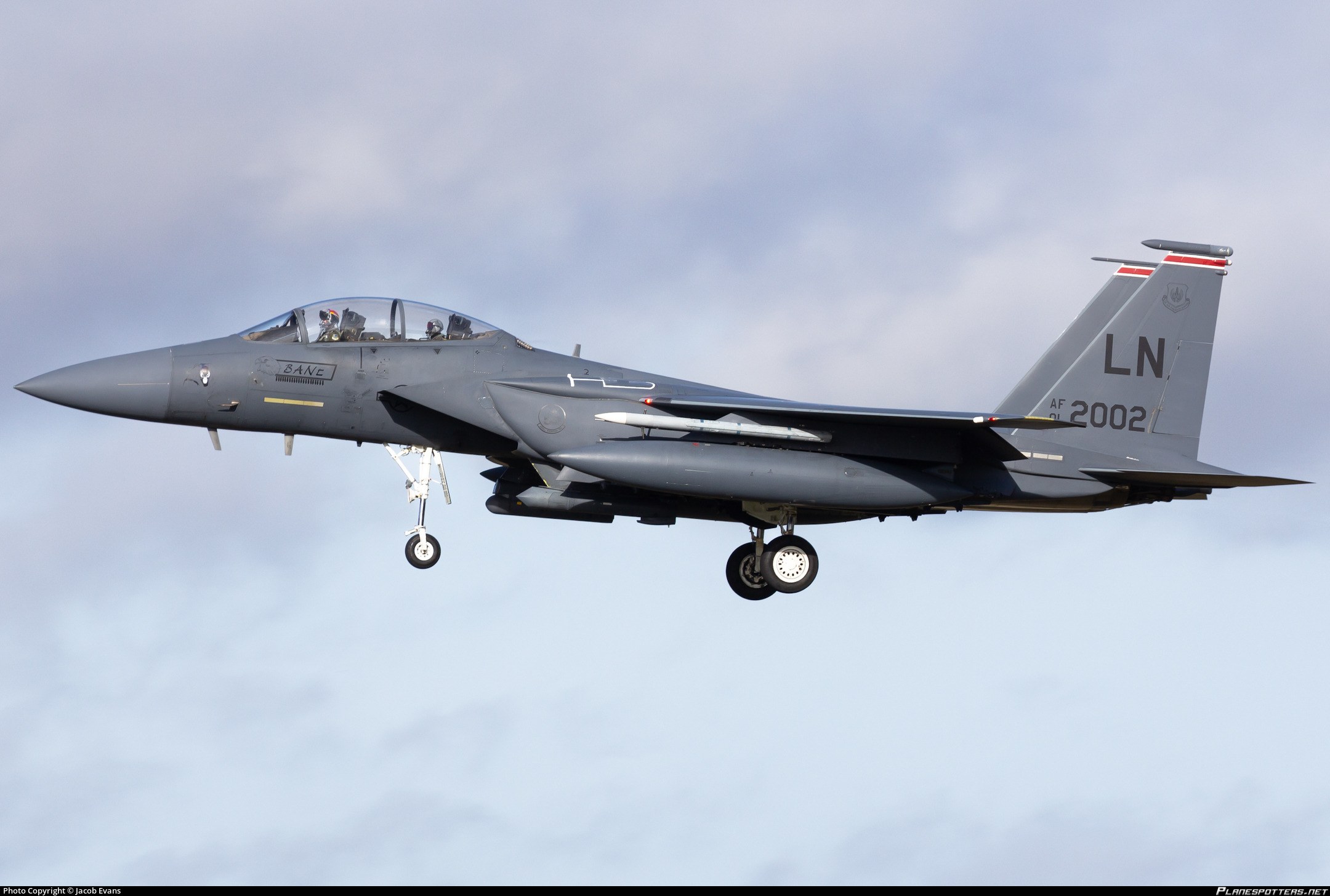 F-15E Strike Eagle marked LN 01-2002 flying side-on with landing gear extended.