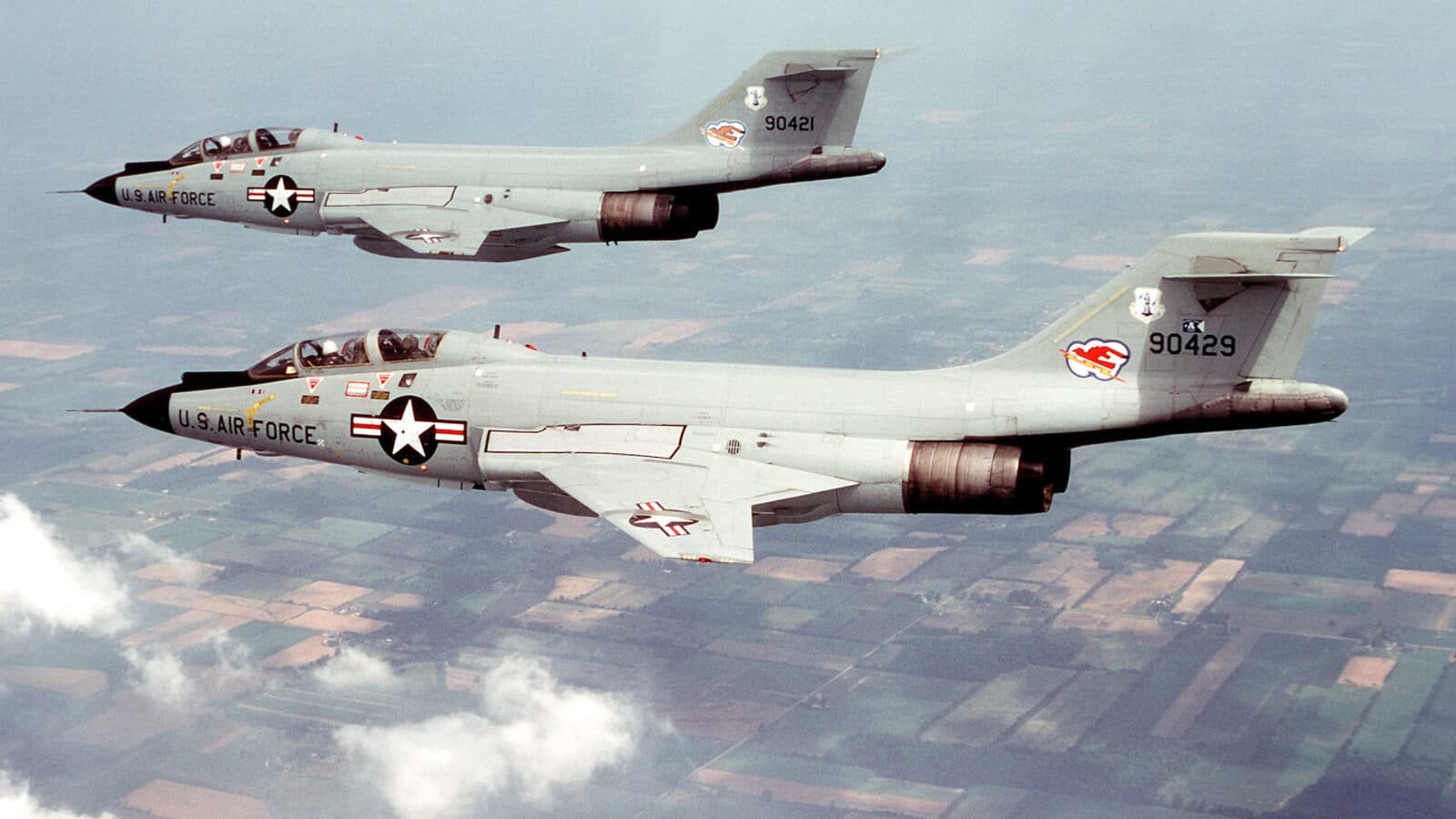 Two U.S. Air Force F-101 Voodoo aircraft flying in formation over farmland.