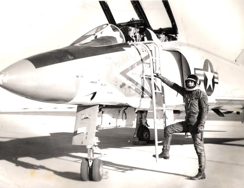 Black-and-white view of an F-4 Phantom II nose and cockpit with a person standing on a ladder.