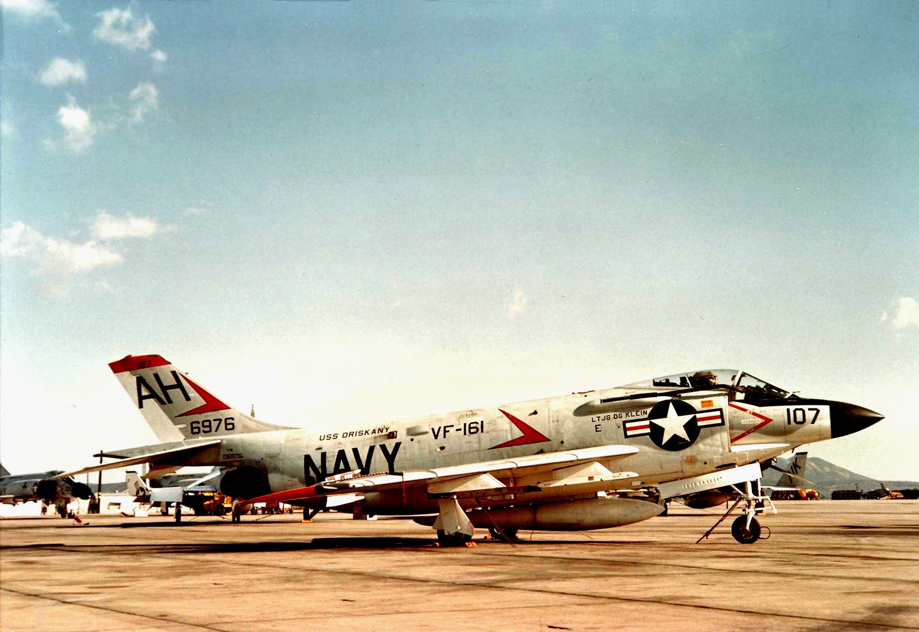 U.S. Navy F3H Demon numbered 107 with tail code AH parked on a ramp.