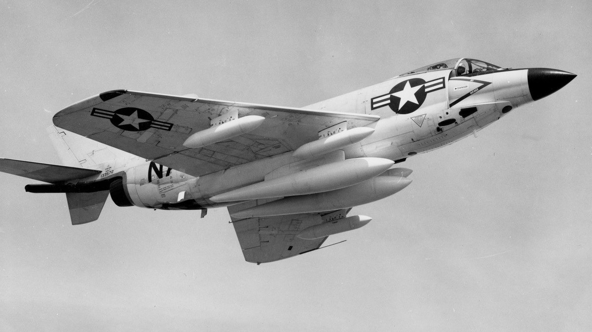 Black-and-white underside view of an F3H Demon flying with gear retracted and underwing tanks.