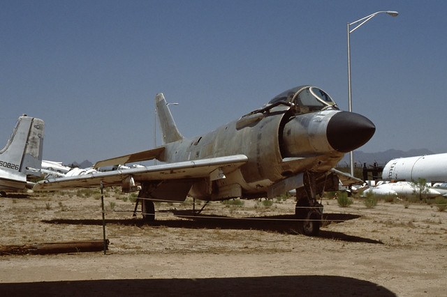 Weathered F3H Demon airframe parked outdoors in a dry storage yard.