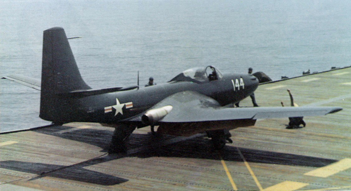 Navy FH Phantom numbered 144 parked on an aircraft carrier deck near the deck edge.