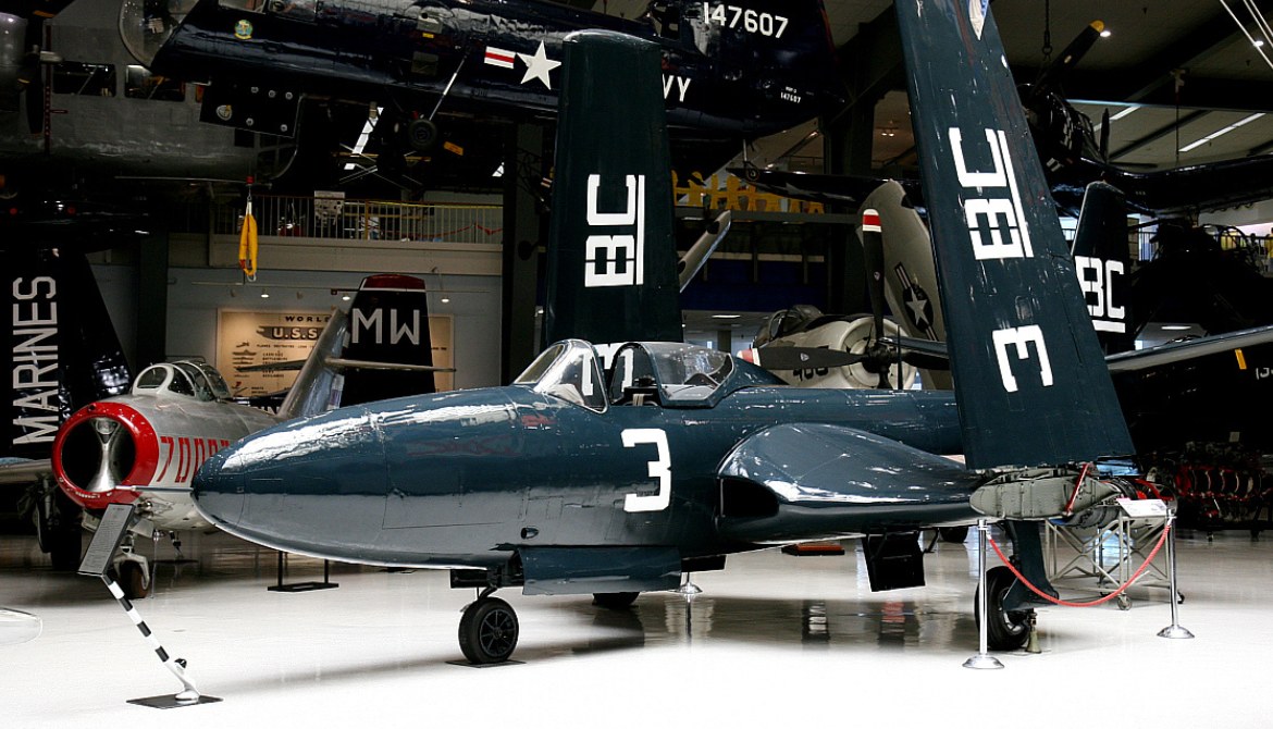 McDonnell FH Phantom number 3 displayed in a museum with folded wings and naval aircraft nearby.