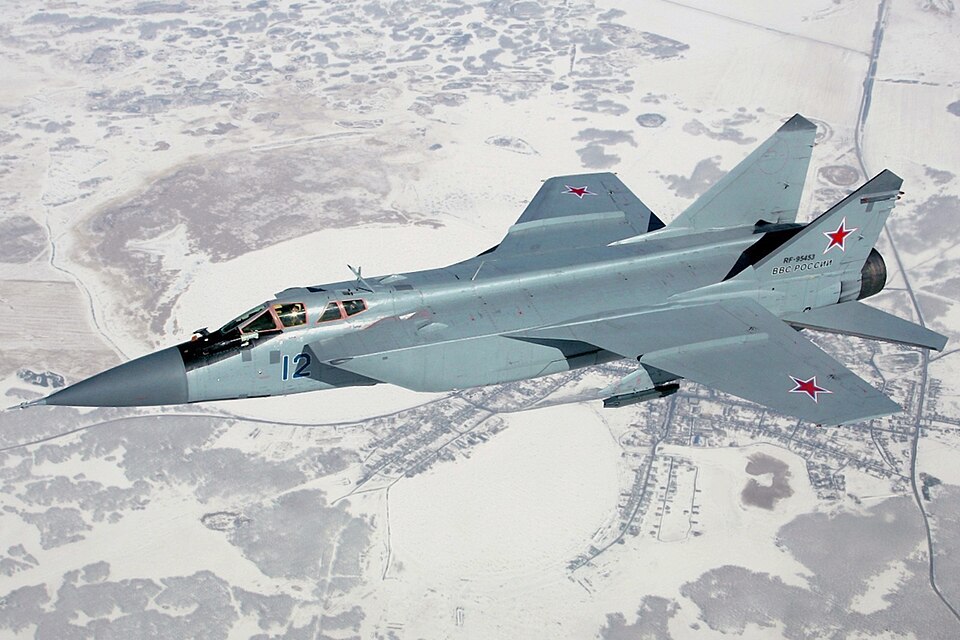 Mikoyan MiG-31 interceptor in flight over snow-covered terrain, showing the long-range high-speed aircraft developed from the MiG-25 line.