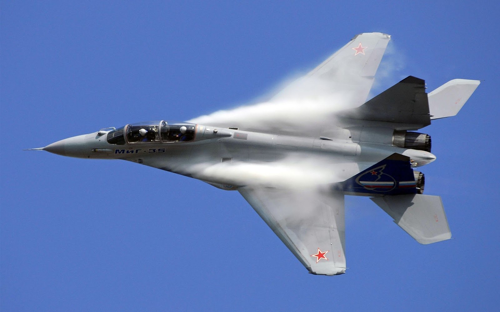 MiG-29 in flight against a blue sky with white vapor forming over the wings.
