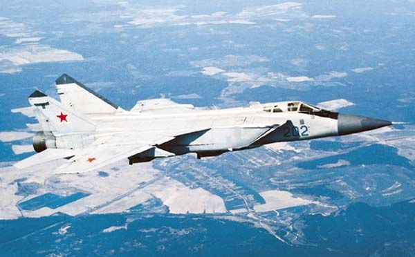 Light gray MiG-31 numbered 202 flying over snowy terrain.