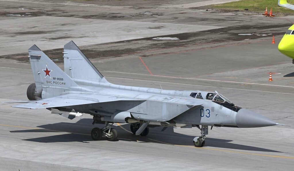 Light gray MiG-31 numbered 03 parked on a ramp with landing gear down.