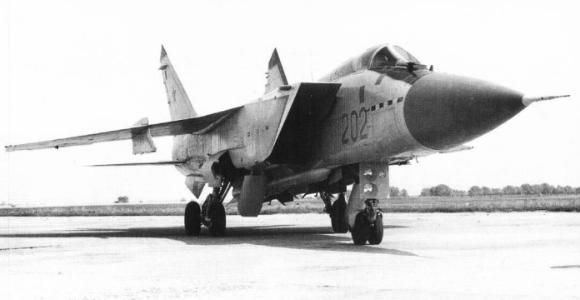 Black-and-white front three-quarter view of MiG-31 202 parked on tarmac with landing gear down.