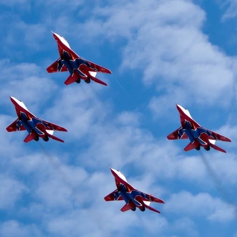 Four red-and-blue twin-tail jets flying in formation against a cloudy blue sky.