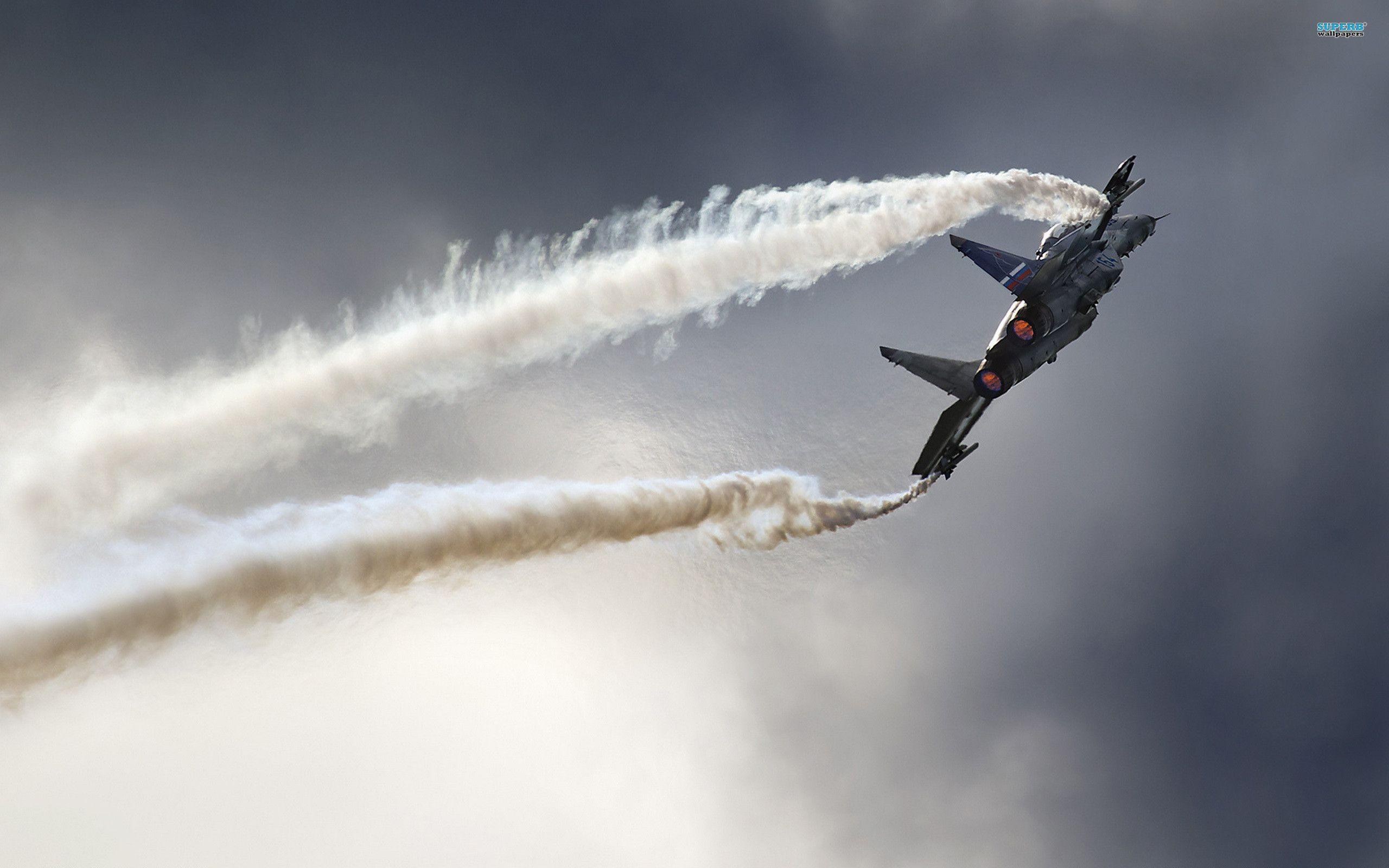Twin-tail jet climbing steeply with thick white smoke trails.