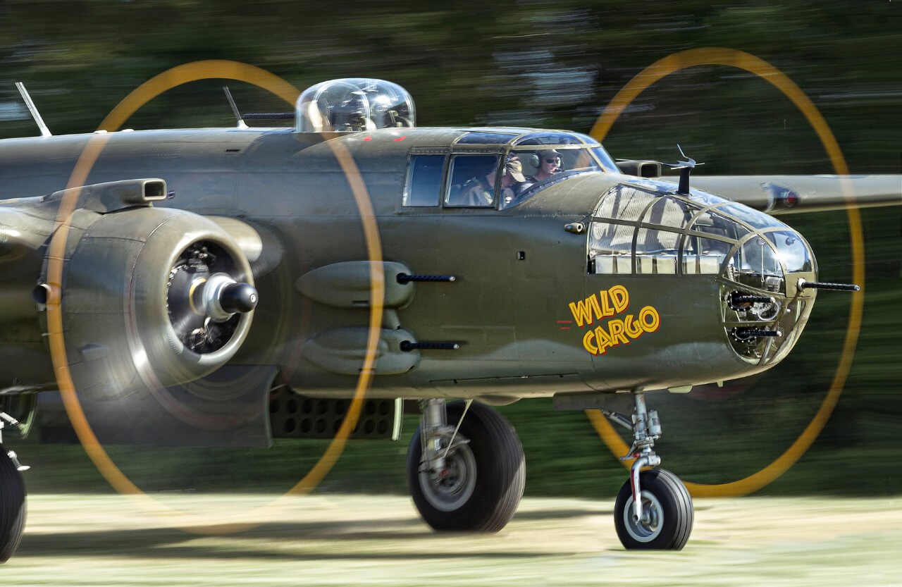 Close view of a B-25 Mitchell nose marked Wild Cargo with both propellers spinning.