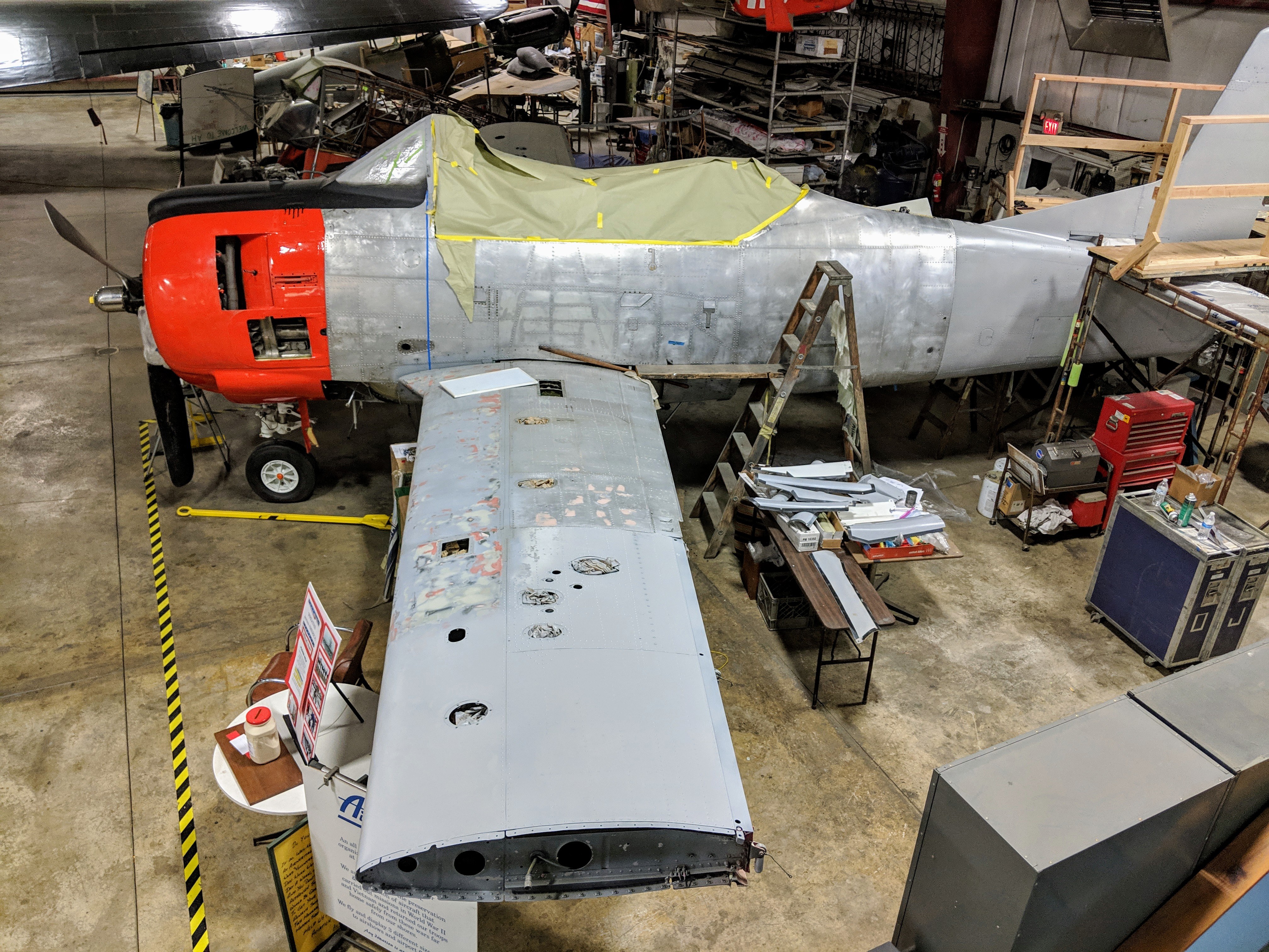 North American T-28 Trojan under restoration in a workshop with wing panel removed.