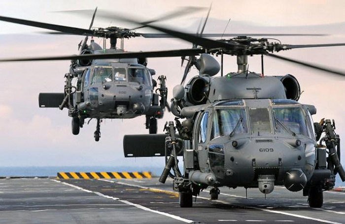 Two Sikorsky HH-60 Pave Hawk helicopters on or above a ship deck.