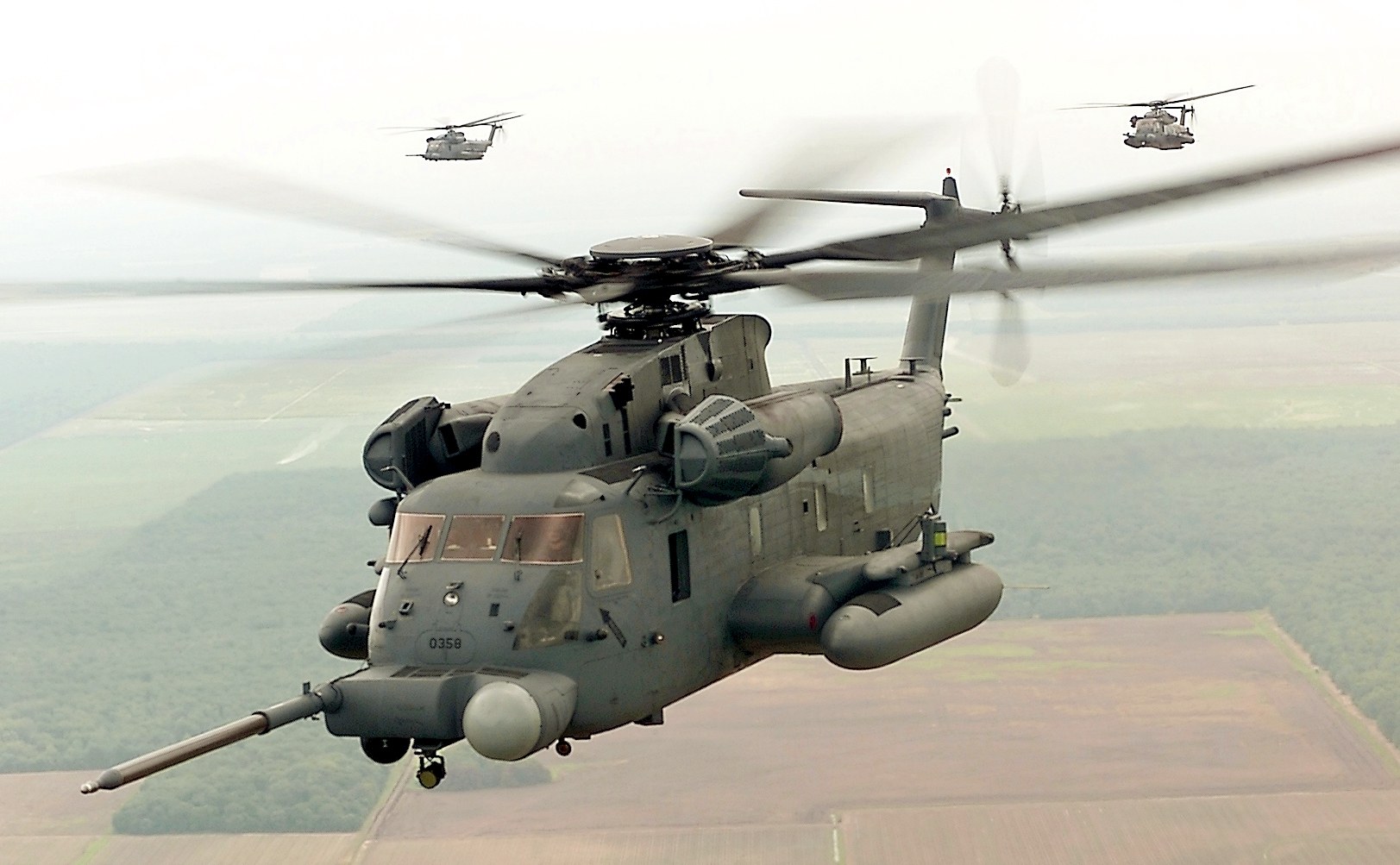 Sikorsky MH-53 Pave Low flying with two smaller helicopters in the distance.