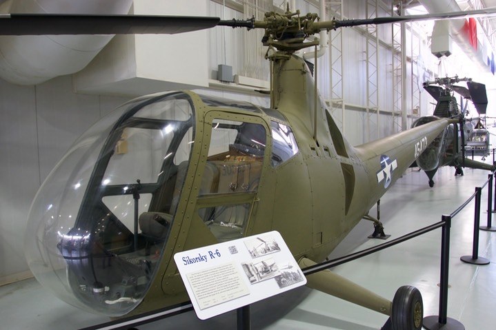 Green Sikorsky R-6 displayed indoors with a clear rounded cockpit nose.