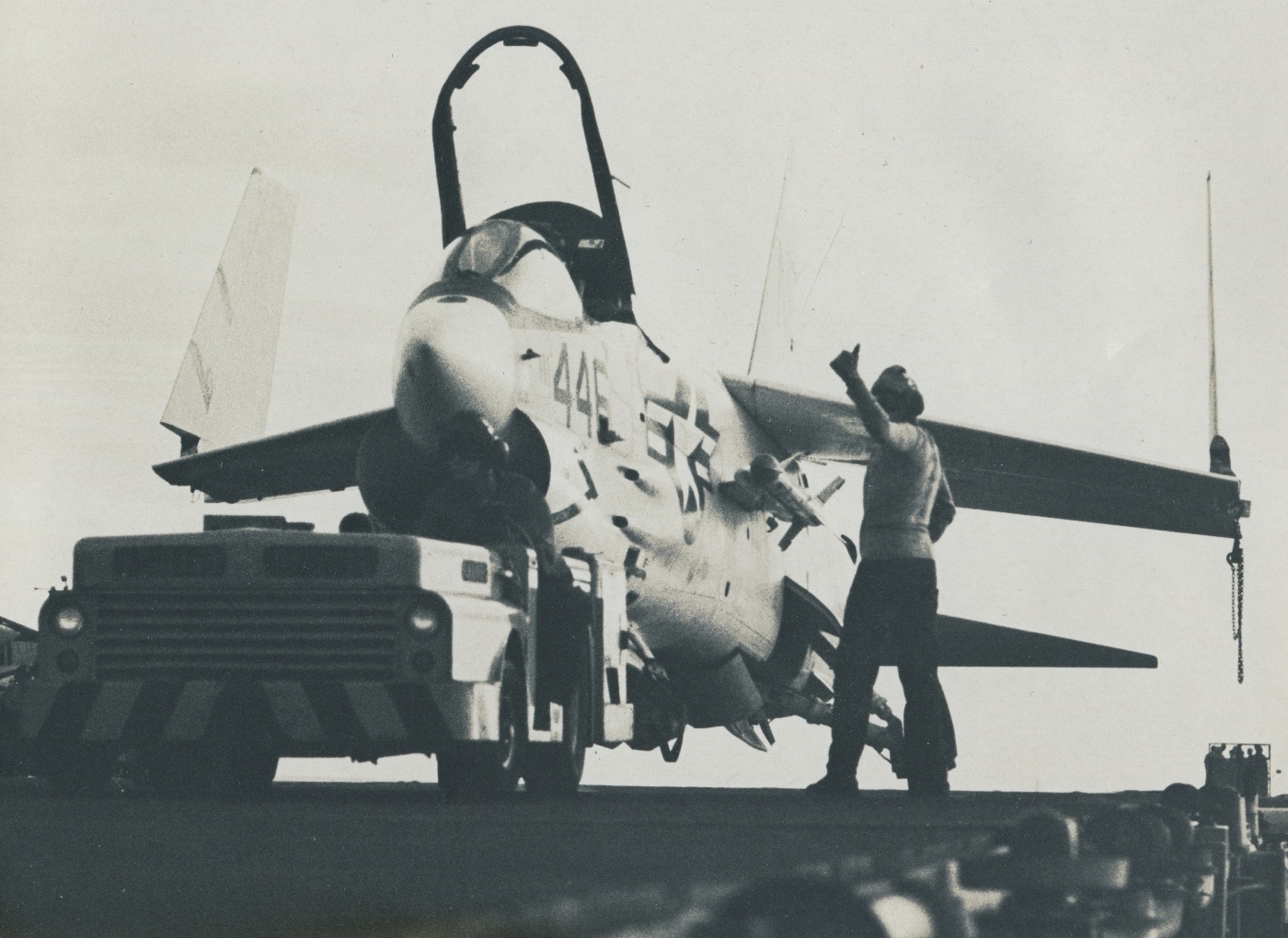 Vought F-8 Crusader - In this photo, U.S. Navy sailors reposition an F-8 Crusader on the deck of an aircraft carrier. The Crusader's prominent turbojet engine ...